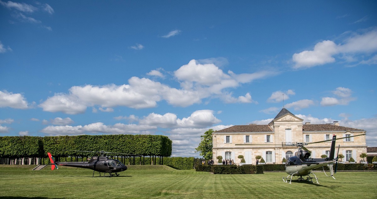 Deux hélicoptères posés sur pelouse, château et vignoble