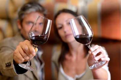Couple qui tient en hauteur un verre de vin rouge et observe sa couleur