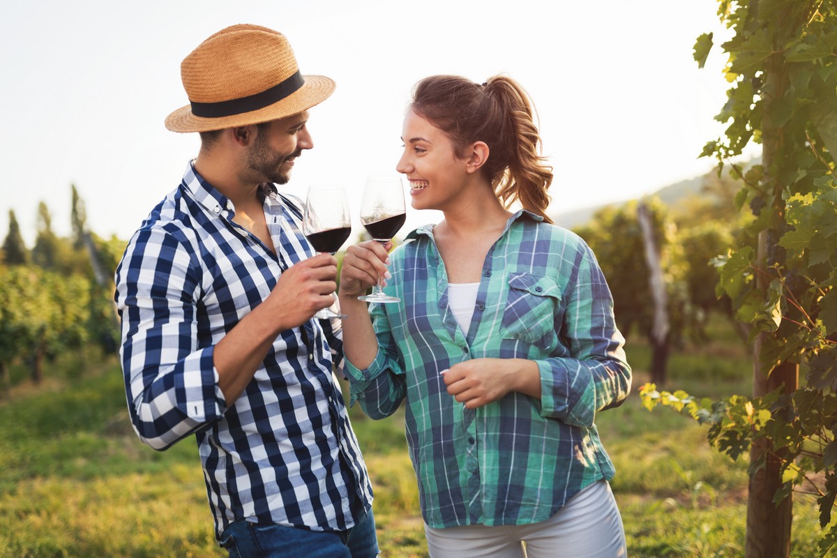 Jeune couple trinque avec verre de vin rouge dans le vignoble