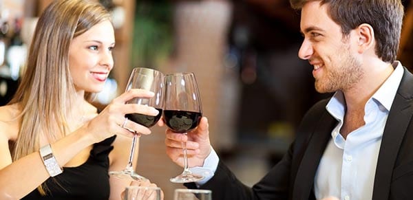 Elégant jeune couple trinque avec un verre de vin rouge les yeux dans les yeux 