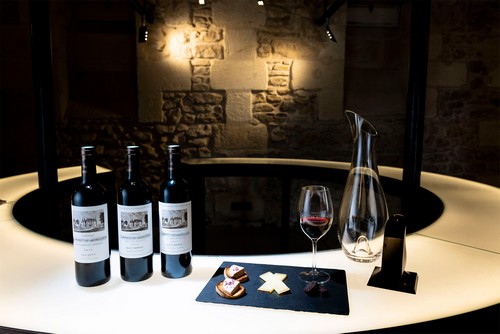 Table de dégustation des vins circulaire, bouteilles vin rouge, carafe et ardoise fromage foie gras