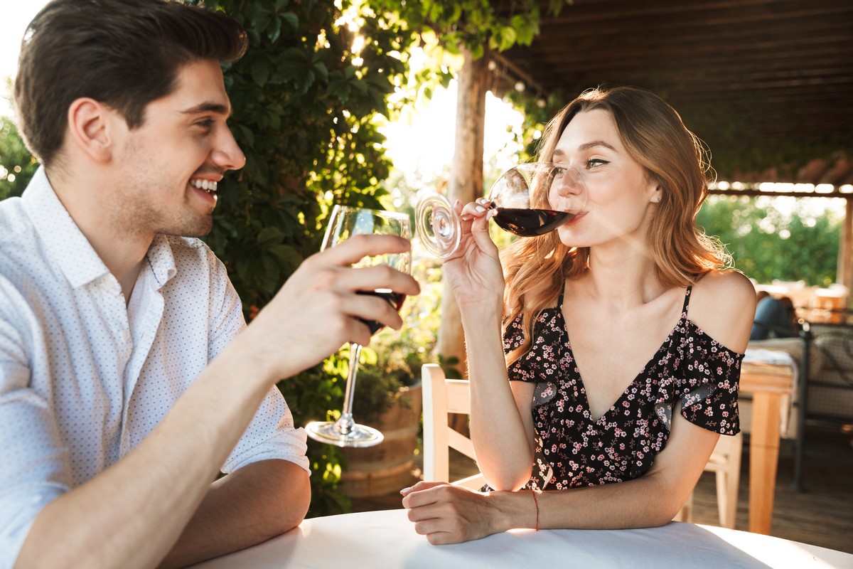 Couple au restaurant en extérieur déguste vin rouge